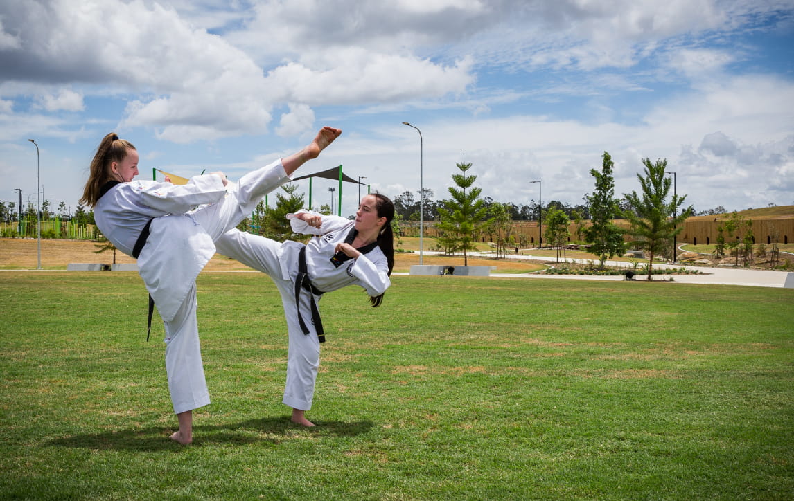 Two girls doing taekwondo in Everleigh park space